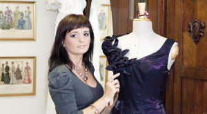 Projektantka Kama Ostaszewska w Atelier z suknią wieczorową na manekinie.