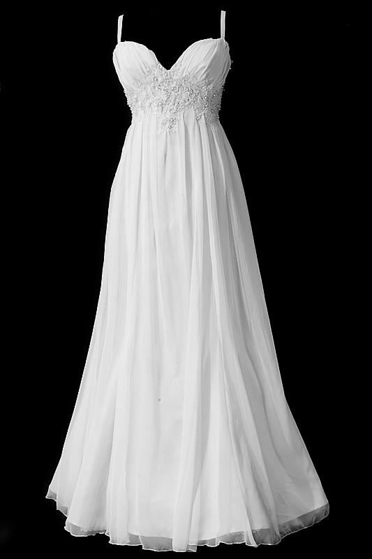 Długa suknia ślubna typu greczynka zbliżona do rybki, z dekoltem w szpic, koronkowymi aplikacjami i gołymi plecami przykrytymi przezroczystą koronką.