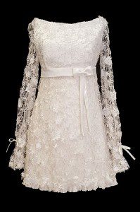 Krótka koronkowa sukienka ślubna z długimi koronkowymi rękawkami i kokardkami.