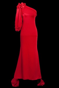 Długa elegancka czerwona suknia wieczorowa z rękawem i odkrytym ramieniem i podpinanym trenem.