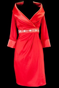 Krótka czerwona suknia wieczorowa z szerokim kołnierzem , długim rękawem i wąskim paskiem zdobionym kamieniami.